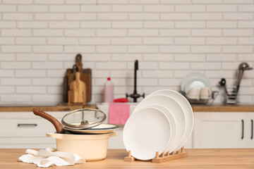 Clean plates, cooking pots and napkin on wooden table in kitchen
