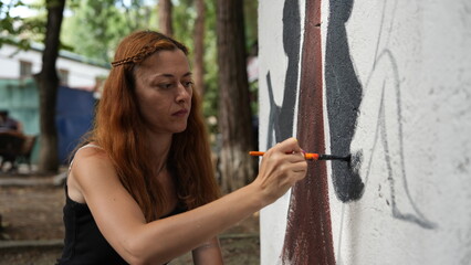 A woman paints a public autism awareness mural. The symbol of autism.