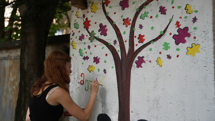 A woman paints a public autism awareness mural. The symbol of autism.