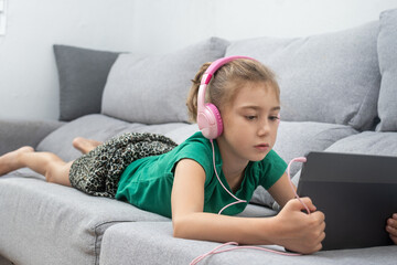 Young Girl Watching Tablet lying on the sofa at home