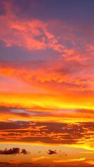 Fototapeta premium A vibrant sunset sky painted in hues of orange, pink, and purple, adorned with fluffy white clouds drifting gracefully across the horizon.