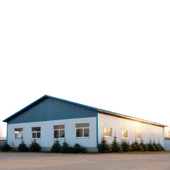 Modern industrial building with blue metal roof and white exterior, surrounded by trees, set against a clear sky, perfect for business or commercial use.