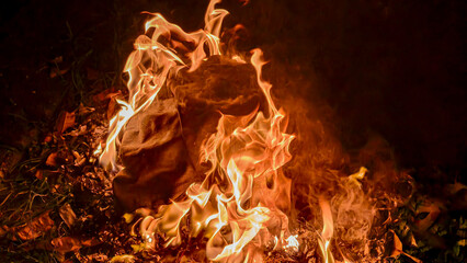 Close-up of bright orange flames engulfing dark material, creating a hot and intense fire.