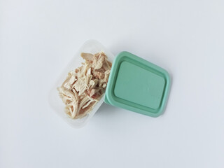 Pieces of chicken fillet in a plastic container with an open lid. White background.