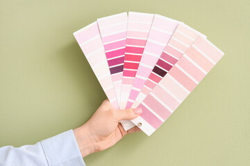 Female hand with pink color palettes on green background
