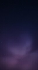 Ethereal nightscape showcasing soft, purple clouds gently whisked across a dark, tranquil backdrop of deep space.