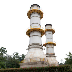 Two tall industrial chimneys with a yellow railing, surrounded by greenery. A symbol of heavy industry and environmental impact.