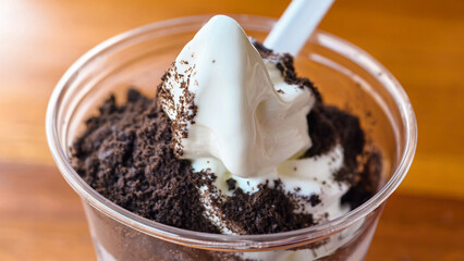 Close-up view of an ice cream dessert with cookie crumbles and a spoon.