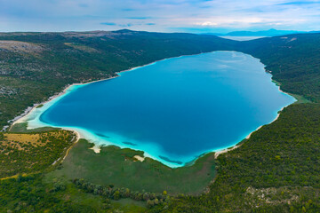 Stunning drone photo of a calm Vransko lake on a Croatian island Cres, surrounded by forest-covered hills and pristine shoreline © TatiG