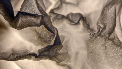 Close-up of textured, translucent paper with soft lighting and shadows creating abstract shapes