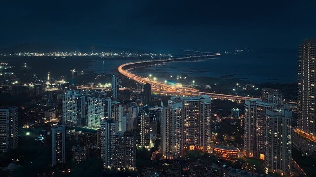 Drone hyperlapse aerial shot of Atal Setu in Mumbai at night, showcasing the dynamic cityscape illuminated with vibrant lights. The footage captures the fast-paced movement of traffic and clouds.