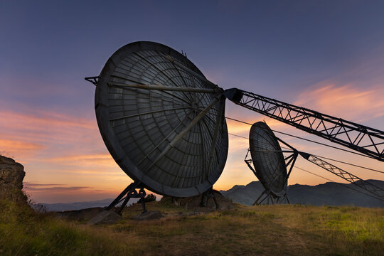 : A dramatic view of decommissioned radar antennas silhouettes against a colorful sunset sky on Monte Giogo in Tuscany, Italy.