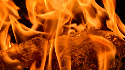 Close-up view of vibrant flames engulfing wood, creating a dynamic and intense visual display.