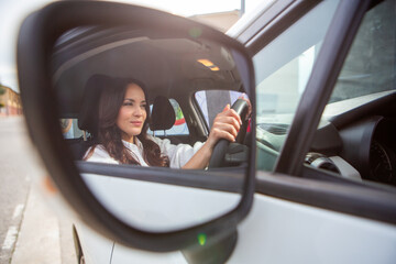 Confident woman focused while driving seen through car mirror