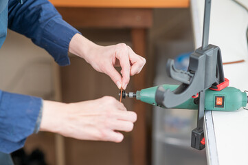 Leatherworker grinding the edge of a strip of leather for a belt in the workshop. 