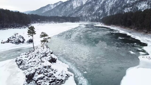A mountain river with a stone island in the middle in winter