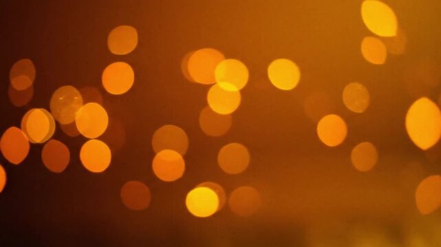 Bokeh of blurred golden orbs of light scattered in a dark warmtoned background