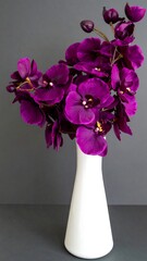 Luxurious Deep Purple Orchid Blooms in a Sleek White Vase Against a Moody Gray Backdrop