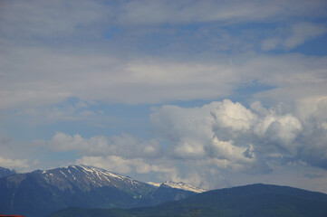 Snowy mountain peaks against the blue sky with white clouds. Sochi, Russia.