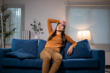 Obraz premium Tired asian woman relaxing on sofa at home after work