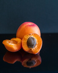 An apricot on the glassy surface. Dark background. Fresh summer's fruits. 