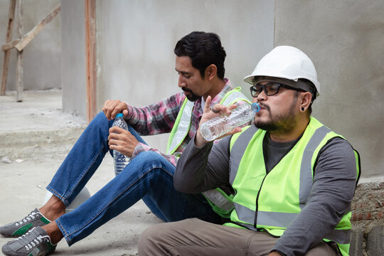 Hopeless builder worker sitting in construction site bend head down in his knee, stressed Asian employee man middle-aged worried about compensation or unemployment, insecurity life insurance planning