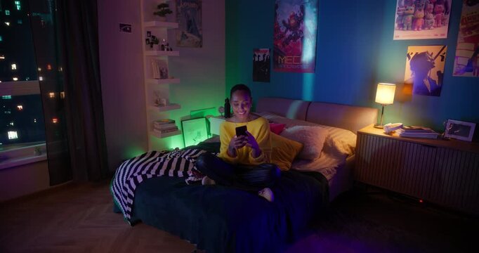 Beautiful African American Female Sitting on a Bed, Using Her Phone to Watch Through Stories, Reels, Short Form Videos and Other Social Media Posts. Dynamic Footage Made with Robotic Cinema Arm