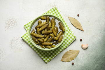 Bowl with tasty pickled cucumbers and different spices on grunge background