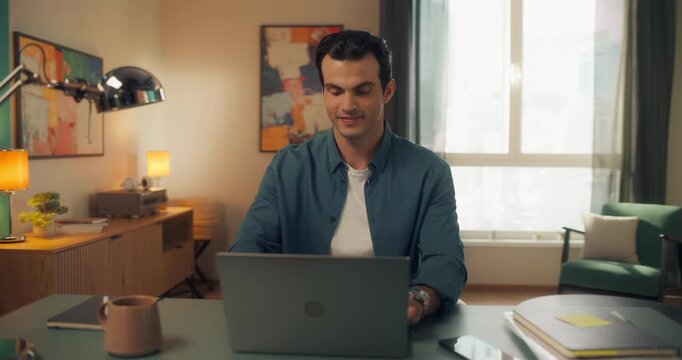 Close Up of a Young Multiethnic Man Opening Up a Laptop and Starting to Work at Home. Male Sitting Behind a Table in Living Room, Using Computer. Dynamic Robot Camera Footage