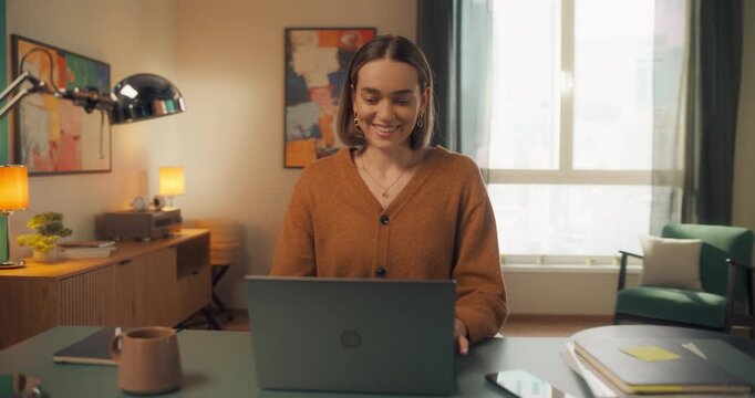 Young Caucasian Female Opening Up a Laptop and Starting to Work at Home. Woman Sitting Behind a Table in Living Room, Using Computer. Dynamic Close Up Portrait Made with a Robotic Camera Arm
