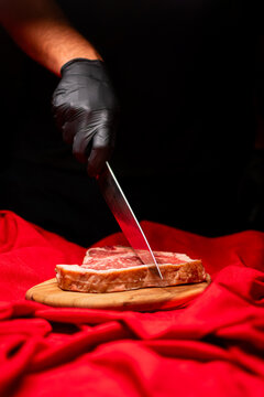 hand holding a knife cutting steak on cutting board