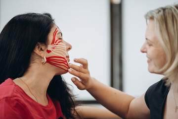 Doctor applying kinesio tape to patient's face for pain relief