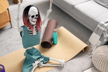 Human skeleton model with wig and sportswear on fitness mat in living room