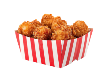 Crispy fried chicken bites served in a striped takeout container at a casual dining location