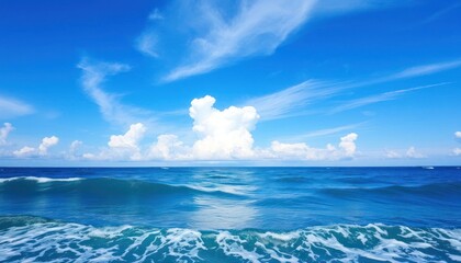 Fototapeta premium A scenic seascape with gentle waves under a vibrant blue sky, dotted with fluffy clouds