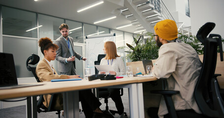 Man draws chart on whiteboard while colleagues sit at table