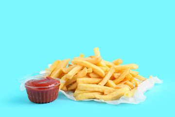 Baking paper with tasty french fries and ketchup on blue background