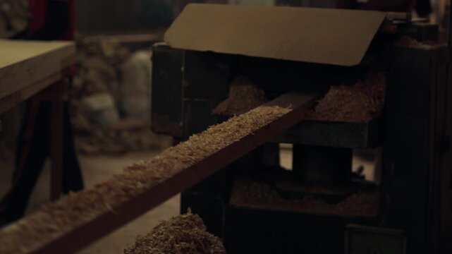 Close-up on Thickness Planer machine, wood worker working in factory, focus on the sawmill is cutting wood in wood factory, covered with dust from the sawdust in the timber factory.