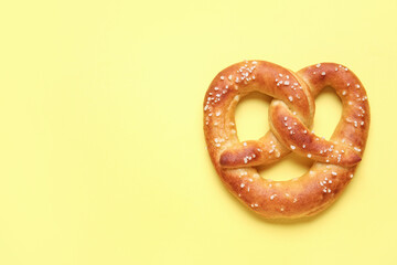 Tasty salted pretzel on yellow background
