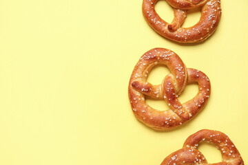 Tasty salted pretzels on yellow background