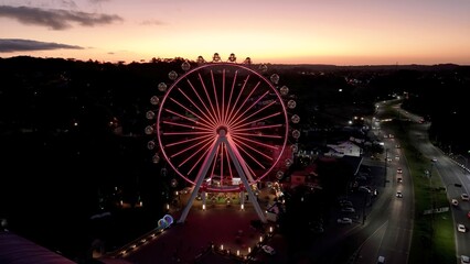Sunset Illuminated Ferris Wheel In Canela Rio Grande Do Sul Brazil. Amusement Park With Various Attractions And Visitors Enjoying. Building Construction Skyline Skyscrapers Awesome.