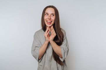 portrait of young woman putting her hands together, showcasing excitement and joy on light...