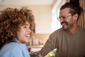 Happy couple laughing together in their modern kitchen