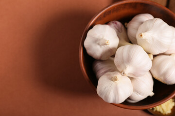 Bowl with fresh garlics on brown background
