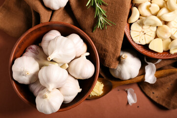 Bowls with fresh garlics on brown background