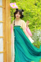 Fototapeta premium Young woman in traditional attire with flower in a garden.