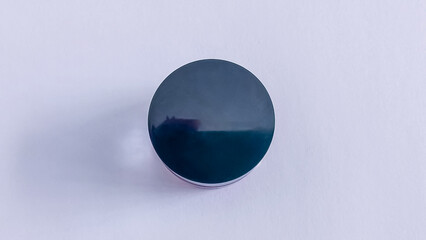 A close-up shot of a circular, dark-colored object on a plain white background