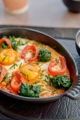 Deliciously Baked Eggs with Spinach, Red Peppers, and Fresh Herbs Served in a Cast Iron Dish for a Hearty Breakfast Experience