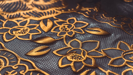 Sophisticated gold floral embroidery on a delicate, dark mesh background creates elegance