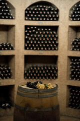 Dark wine cellar interior with arched walls. Aged wine bottles stored in underground cellar. Vintage wine cellar. Rustic and atmospheric.